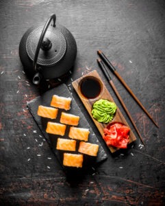 Philadelphia sushi roll on a stone stand with ginger, wasabi and soy sauce.