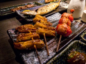 Set of delicious traditional skewers grilled for dinner. Popular Japanese variety food in the restaurant. Appetizing Japan skewer plate on wooden table.